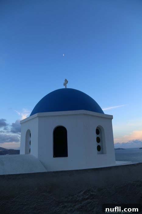 Close-up shot of the white buildings and blue domes of Santorini, bathed in the soft, warm light of the setting sun.