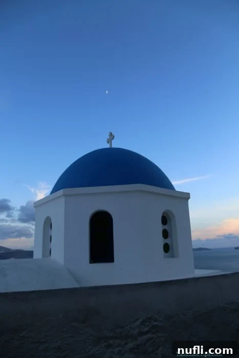 Close-up shot of the iconic blue-domed white buildings in Oia, Santorini, bathed in the soft, warm light of the setting sun.