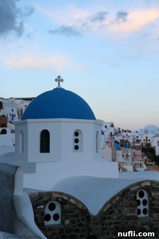 An intricate view of Santorini's unique architectural blend of white buildings and vibrant blue domes, captured during the twilight hours.