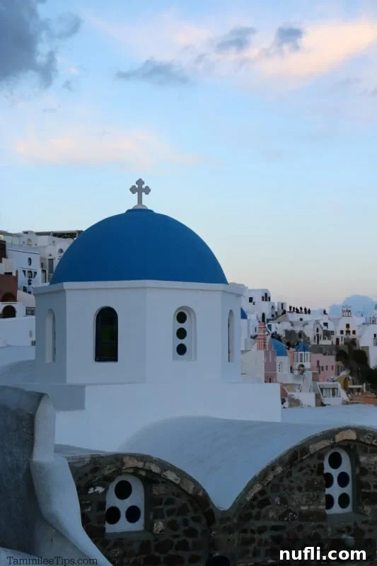 Panoramic view of the charming blue and white buildings of Oia, Santorini, with the caldera cliffs in the background.
