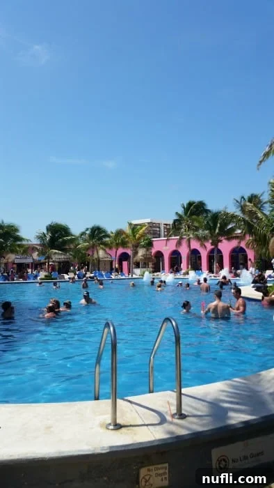 Inviting saltwater pool area with towering palm trees and people swimming and lounging around