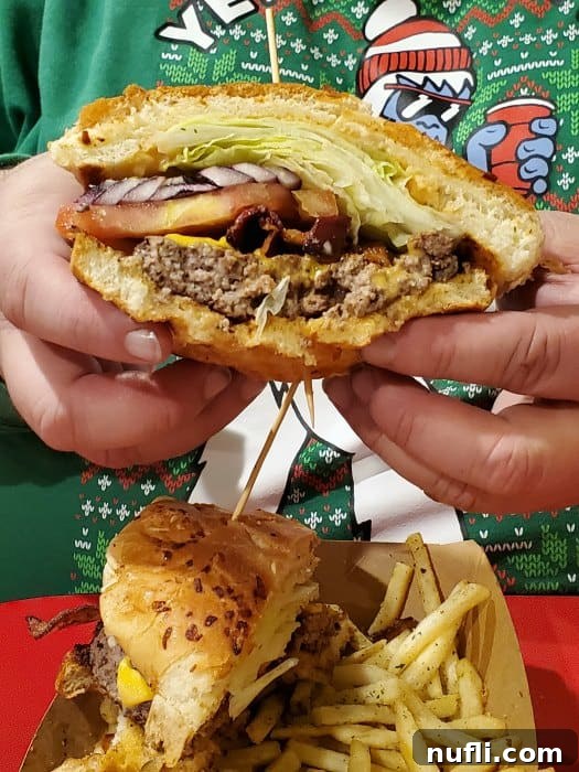 A hand holding a massive, mouth-watering burger, showcasing its impressive size