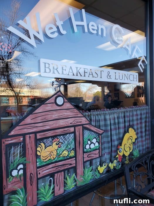 Wet Hen Cafe breakfast and lunch sign, adorned with charming chicks painted on the window