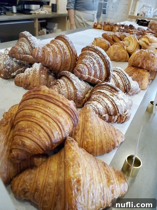 Artisanal croissants perfectly lined on a bakery shelf, invitingly golden-brown