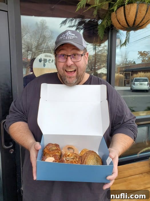 John smiling, holding a stylish blue box filled with delightful pastries from Perenn Bakery