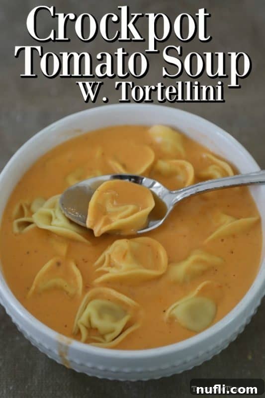 Crockpot Tomato Soup with Tortellini over a white bowl with soup and a spoon holding a piece of tortelini 