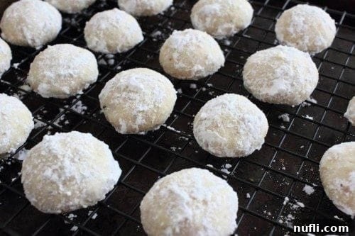 Snowball cookies cooling on a metal drying rack