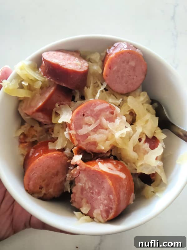 Kielabasa and sauerkraut in a white bowl with a fork