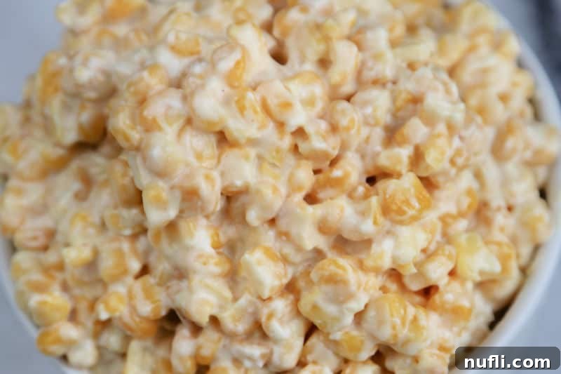 Close-up shot of rich and creamy slow cooker creamed corn in a white bowl, highlighting its inviting texture.