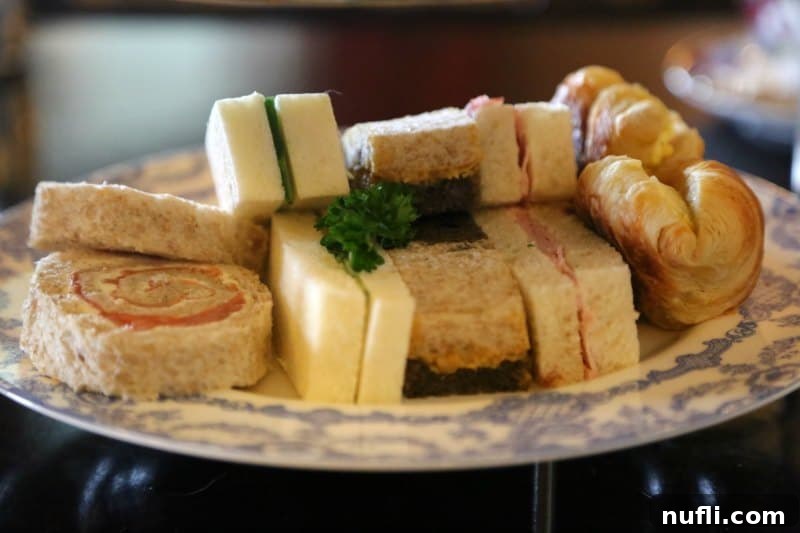 A selection of gourmet tea sandwiches beautifully arranged on a tiered tea plate, featuring various fillings.