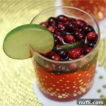 Cranberries and lime in a red cocktail in a glass with gold polka dots