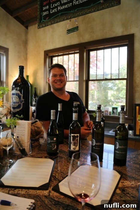 Man behind the bar smiling with Dunham Cellar wine bottles 