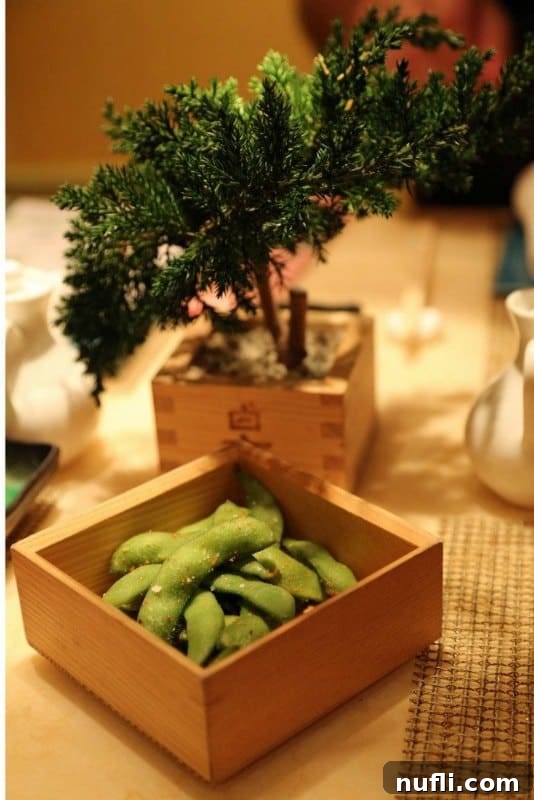 Edamame in a wooden bowl by a bonsai