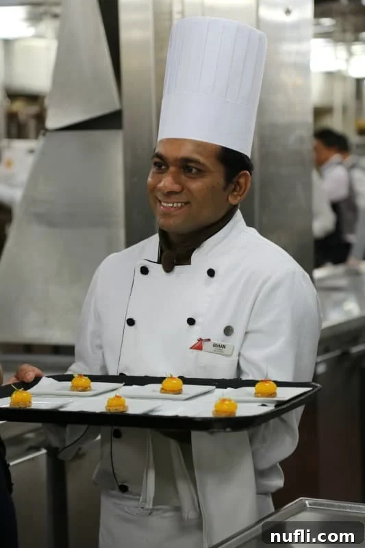 A Carnival chef proudly holding a platter of exquisitely presented gourmet food.