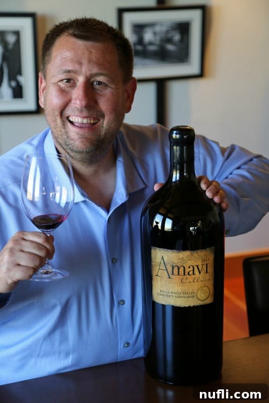 A cheerful individual, John, proudly posing with an impressively large bottle of Amavi Wines and a standard wine glass, highlighting the grandeur of their offerings