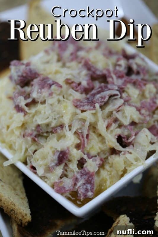 Easy Crock Pot Reuben Dip 2 Creamy, golden brown crockpot reuben dip in a white bowl, garnished with fresh parsley, surrounded by toasted rye bread squares and various crackers.