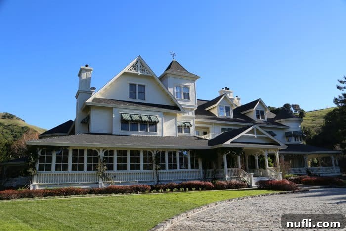 The grand exterior of the Main House at Skywalker Ranch, featuring intricate architectural details and a welcoming, large white porch, exuding a timeless elegance amidst its natural surroundings.
