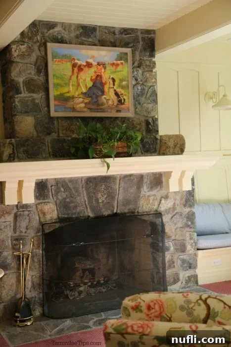 An elegant painting hangs above a rustic rock fireplace, with a comfortable floral-patterned armchair positioned in front, creating a cozy yet sophisticated ambiance within the technical building.
