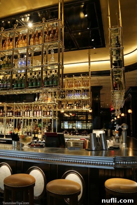 Glass shelves filled with a vast selection of bottles over the meticulously arranged bar at Bardot Brasserie.