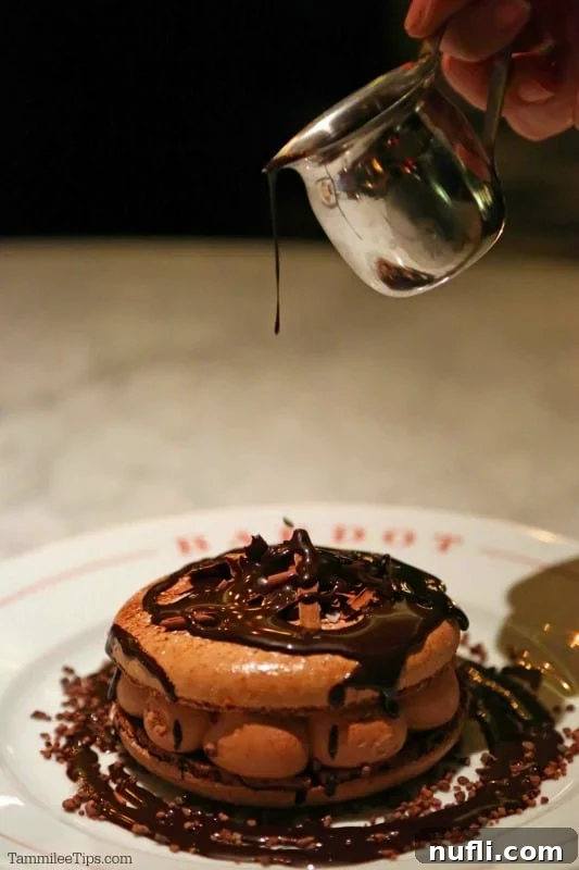 Molten chocolate being drizzled dramatically over a large, decadent chocolate macaron, creating an irresistible cascade.