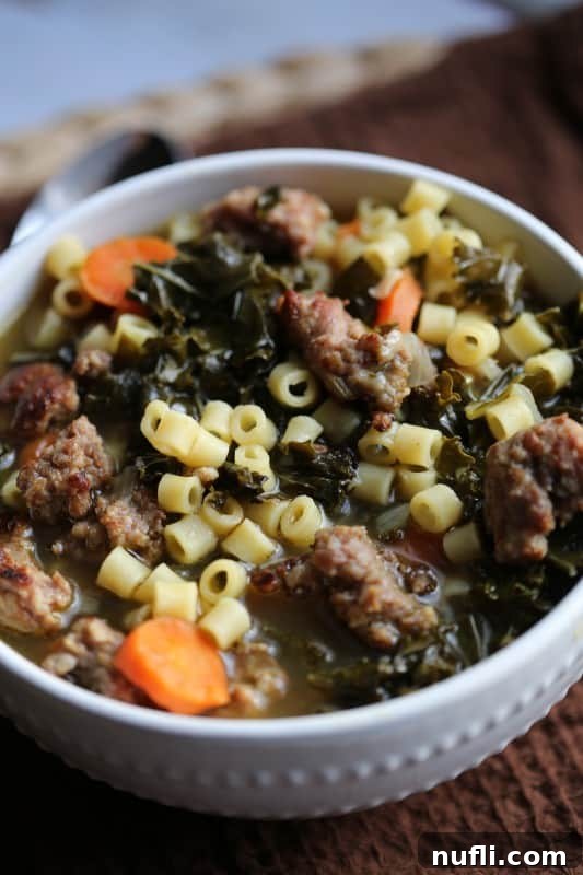 A top-down view of Crock Pot Italian Sausage Wedding Soup Recipe, highlighting the rich broth and colorful ingredients like carrots and kale.