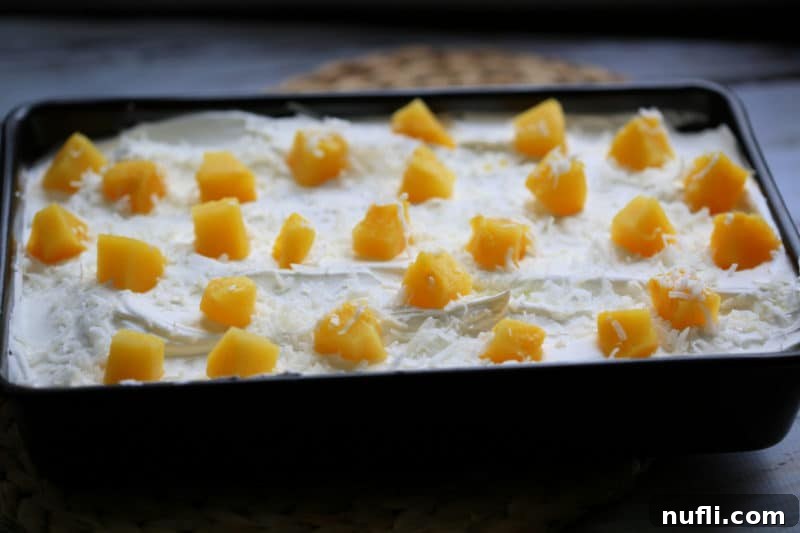 Pina Colada Poke Cake in a cake pan topped with pineapple chunks