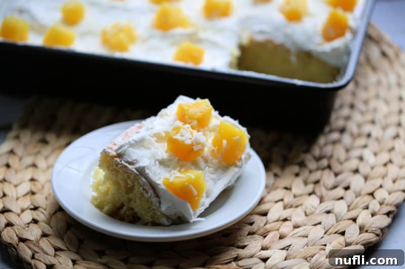 Slice of Pina Colada Poke Cake on a white plate next to the cake pan