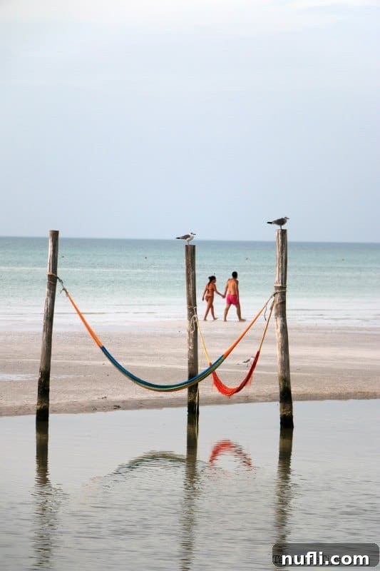 An Idyllic Photo Journey Isla Holbox Mexico 14 Hammocks over the water with a couple walking the beach