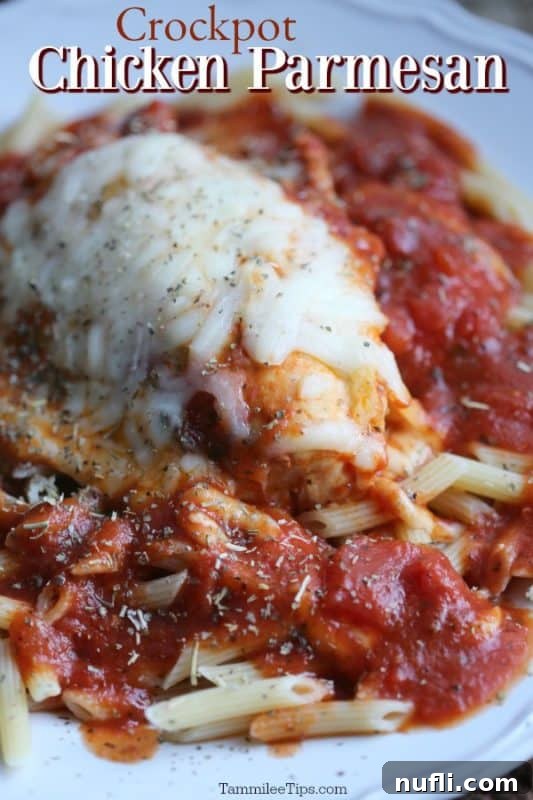 crockpot chicken parmesan over a chicken breast with melted mozzarella, on top of penne pasta with sauce