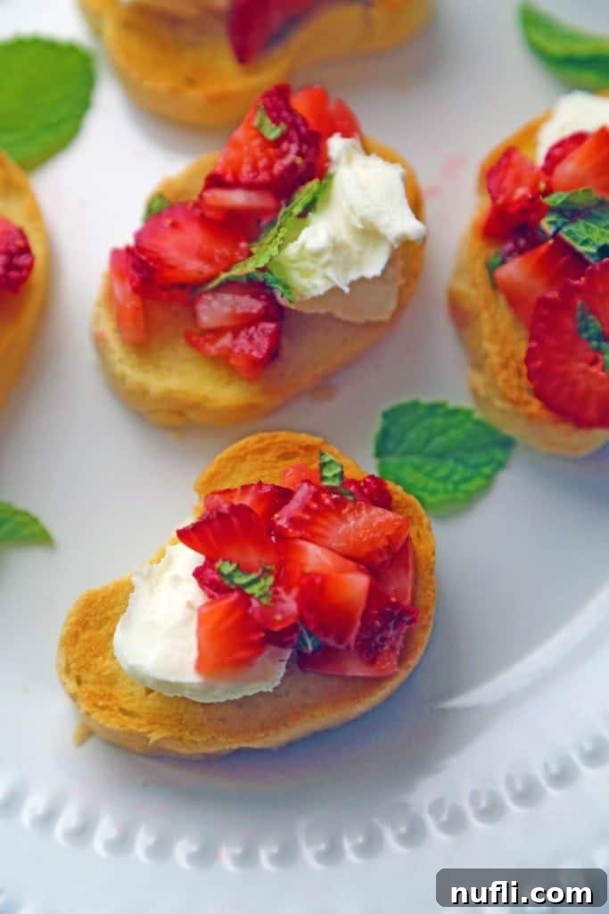 A delightful Strawberry Bruschetta, featuring fresh strawberries and creamy ricotta cheese, elegantly presented on a slice of toast on a white plate.