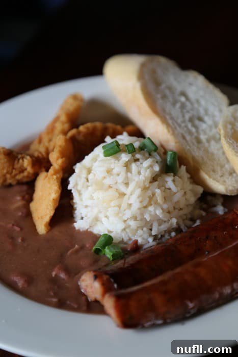 A classic New Orleans dish of red beans and rice with savory sausage on a white plate, served at Chartres House.