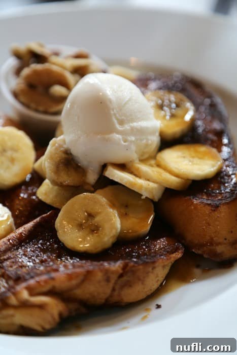 Decadent Bananas Foster French Toast on a white plate, topped with caramelized bananas and sauce, from Stanley Restaurant.