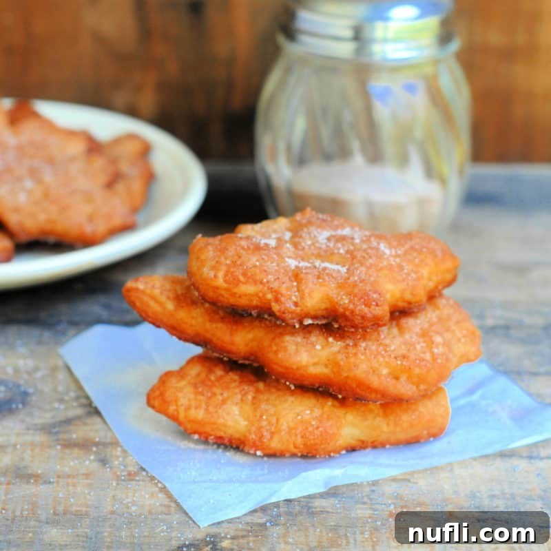 Cinnamon And Sugar Crescents stacked on a paper napkin near a plate and sugar container