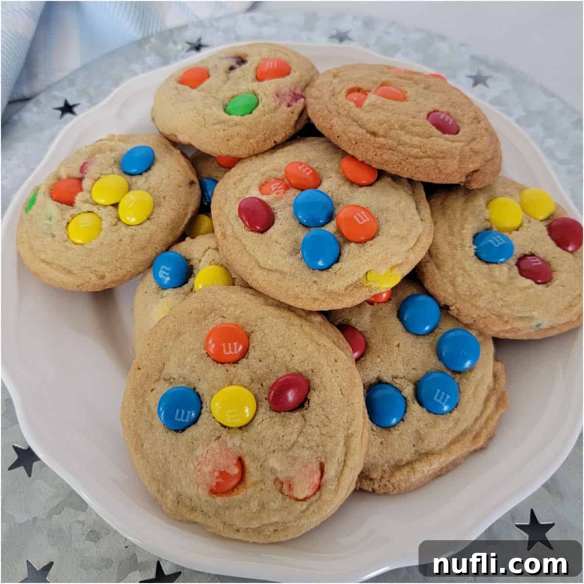 Colorful M&M cookies stacked on a white plate with star decorations