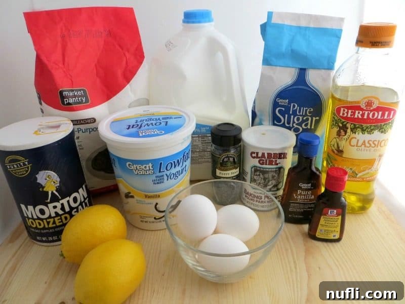 flour, milk, salt, yogurt, sugar, oil, baking powder, lemons, eggs, poppy seeds, vanilla, and almond extract on a cutting board. 