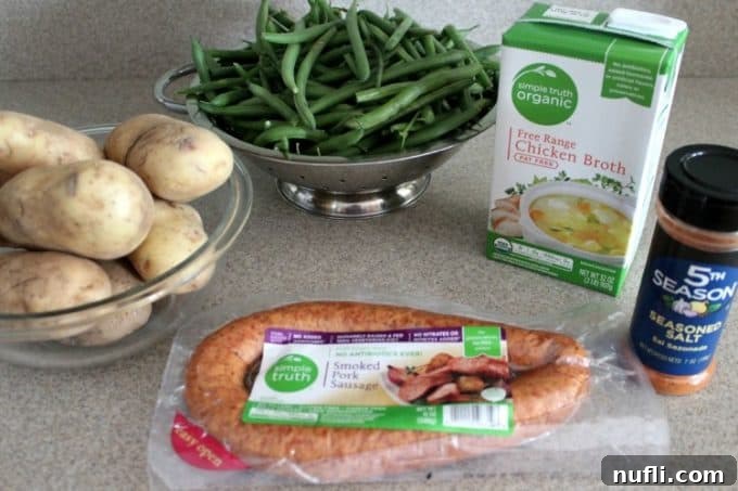 Raw ingredients for Crockpot Kielbasa and Green Beans with Potatoes, including sausage, green beans, potatoes, and seasoning salt.