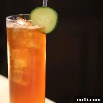 Pimm's Cup in a tall glass with cucumber wheel garnish