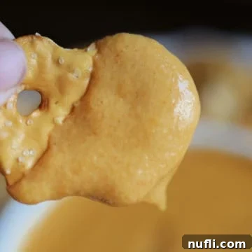 Bagel chip covered in Guinness Beer Cheese Dip above a bowl