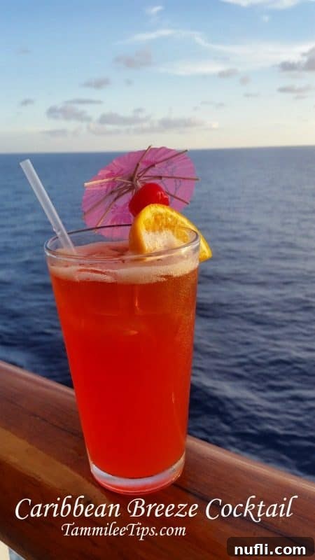Vibrant red Caribbean Breeze cocktail on a cruise ship railing with the expansive blue ocean in the background, hinting at tropical adventure and relaxation.