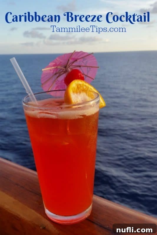 Close-up of a vibrant red Caribbean Breeze cocktail, garnished with an orange slice and a cherry, set against a blurred tropical ocean backdrop. The text reads: 'Enjoy a reminder of your amazing Carnival Cruise vacation at home with this Caribbean Breeze Cocktail! The perfect tropical drink for summer!'