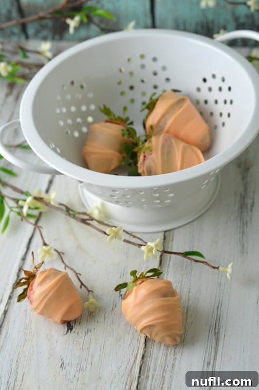 Arrangement of chocolate-covered strawberries shaped like carrots in a white bowl and on a wooden table, ready for Easter