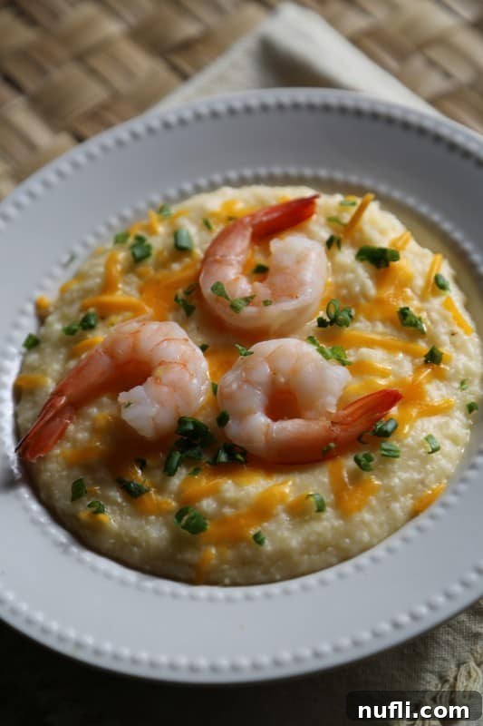 Crockpot Shrimp and Grits in a white bowl with green onion and cheddar cheese garnish