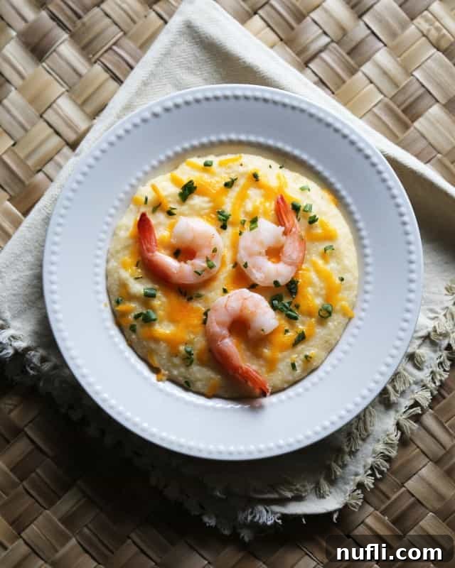 Crockpot Shrimp and Grits in a white bowl with green onion and cheddar cheese garnish
