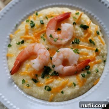 Crockpot Shrimp and Grits in a white bowl with green onion and cheddar cheese garnish