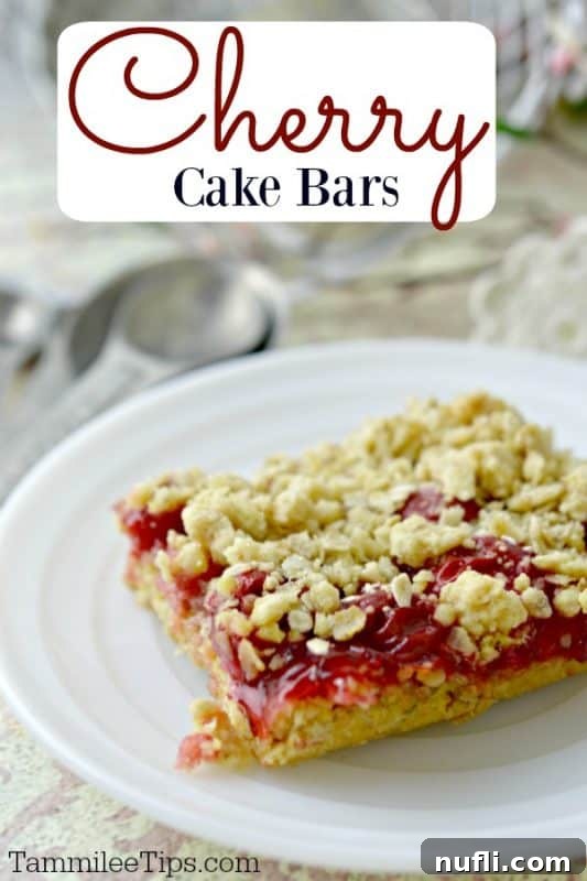 A square cherry cake bar on a white plate, showcasing its golden crust and vibrant cherry filling.