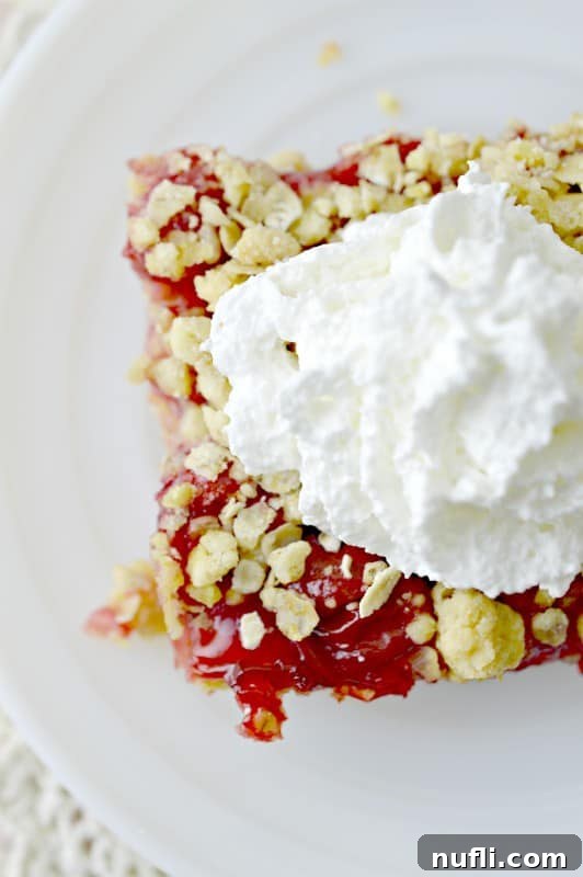 A single square cherry cake bar on a clean white plate.