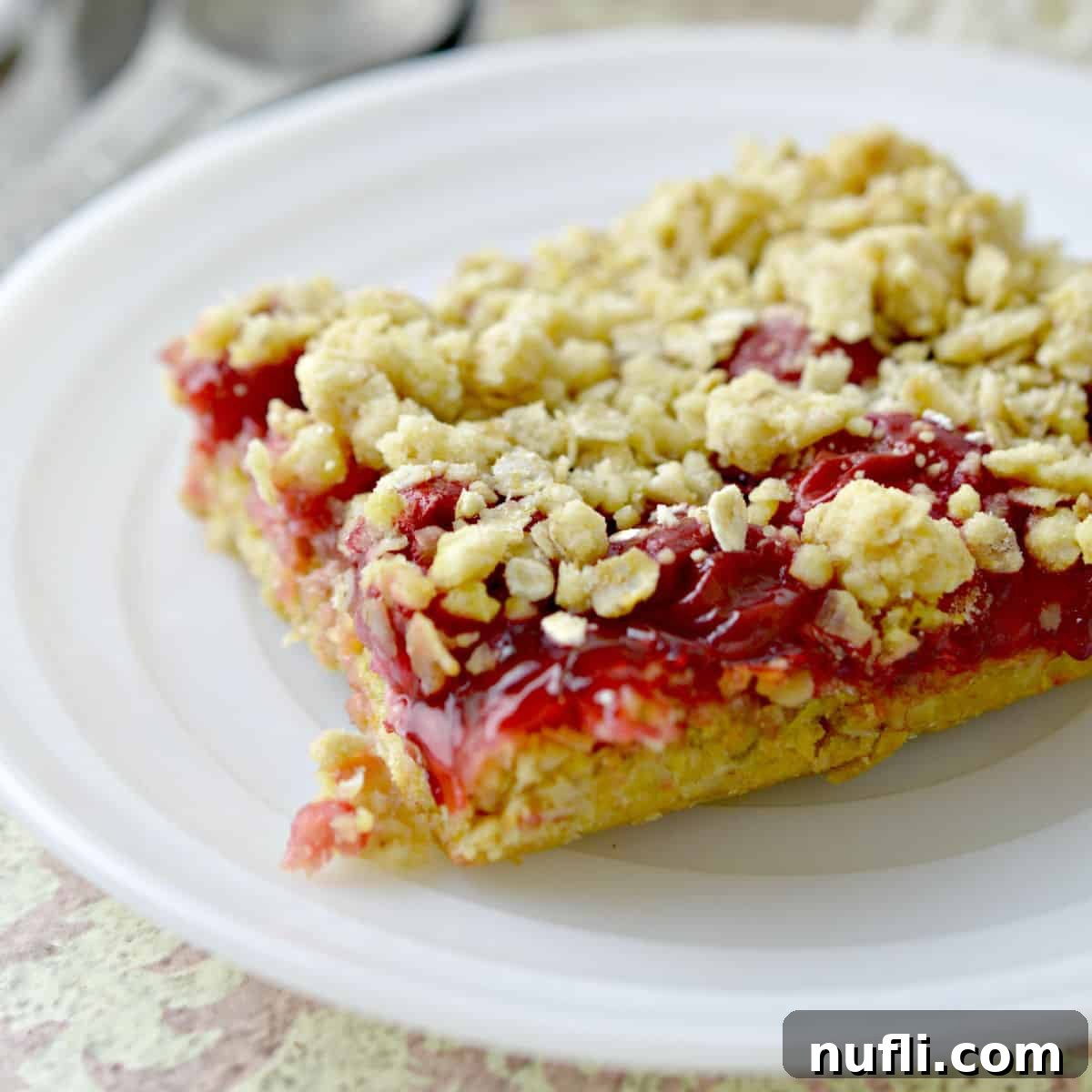 A single square cherry cake bar on a clean white plate.