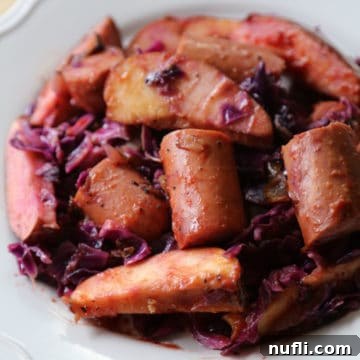 Crock Pot Kielbasa with Red Cabbage and Apples 4 kielbasa, red cabbage, and apples on a white plate