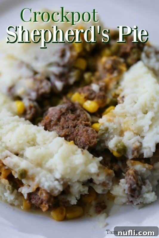 Hearty Crockpot Shepherd's Pie served on a white plate with a spoonful of cheesy mashed potatoes and beef filling