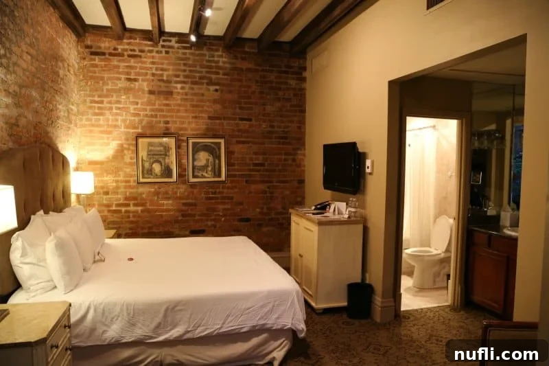 Dauphine Orleans Hotel New Orleans 4 hotel room with bed, nightstands, brick wall and looking towards the restroom